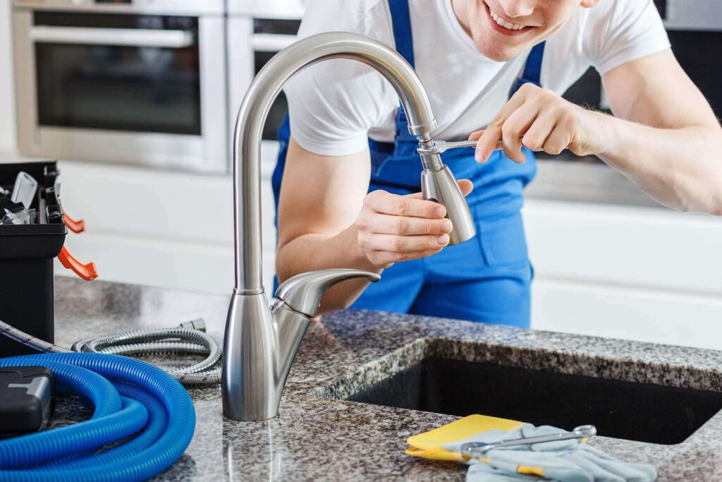 close smiling plumber fixing faucet